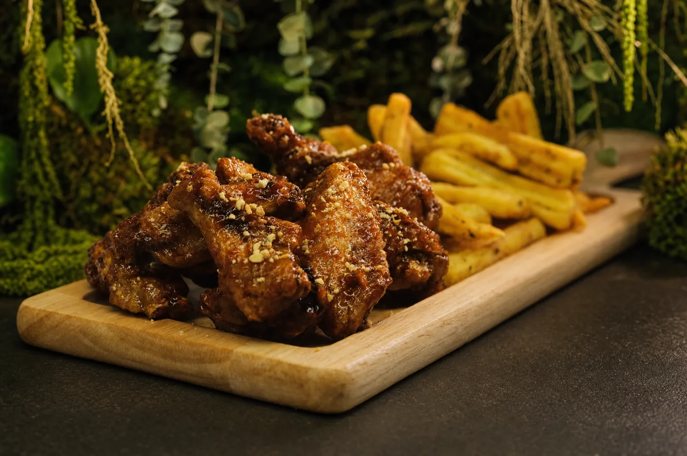 Crispy wings on a wooden board, with fries