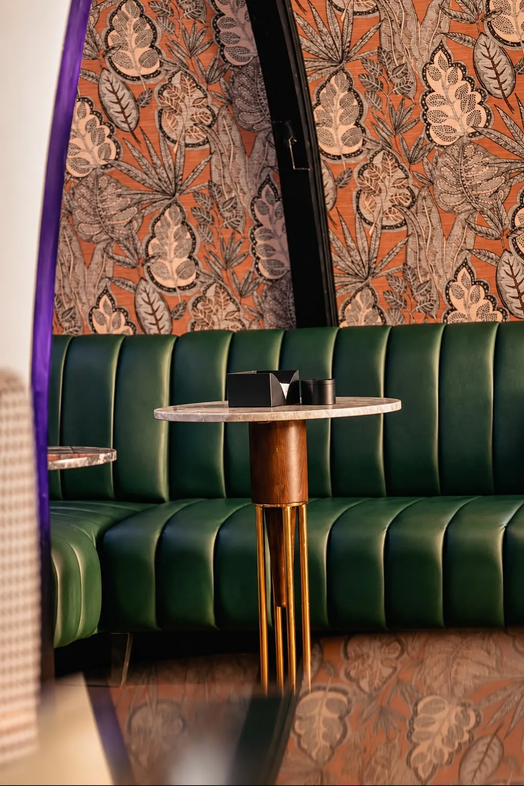 Green leather booth under leaf wallpaper
