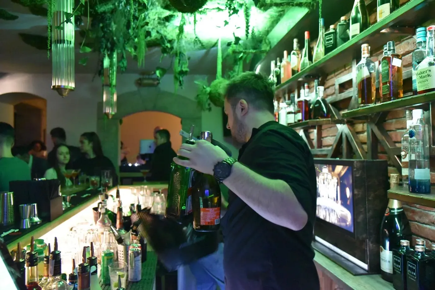 The bartender pouring, under green light